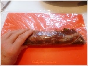 Roll the fillet around the stuffing and inside the cling film, pushing away from you